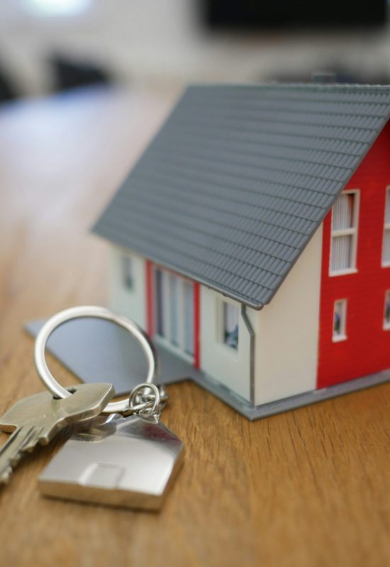 A small toy house on a desk next to a real keychain house key